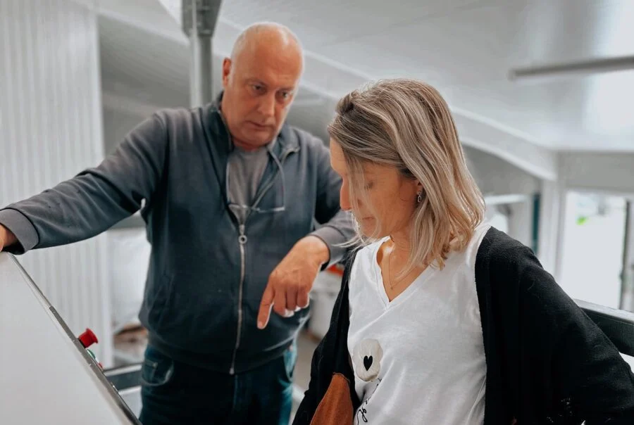 Two members of the team in front of the pressing line, in the laboratory
