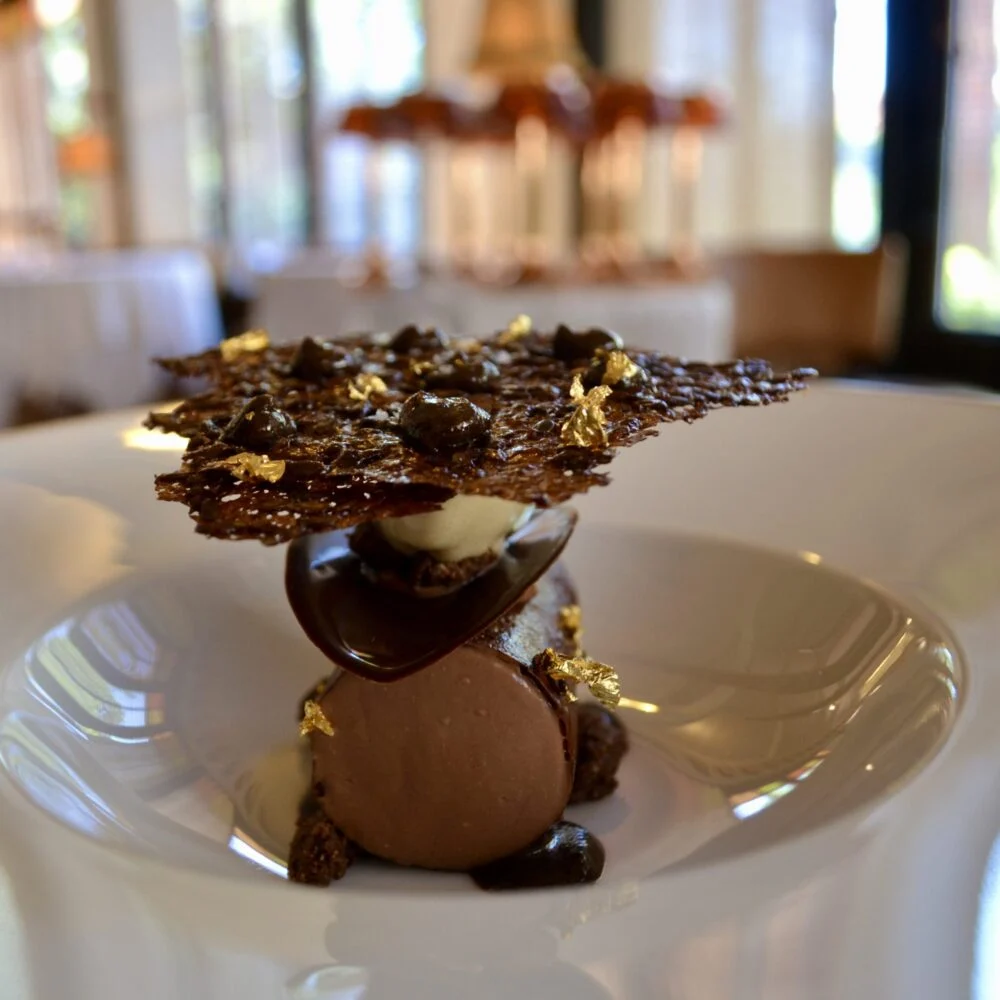 A chef's plated dessert, with a kibbled flaxseed tuile