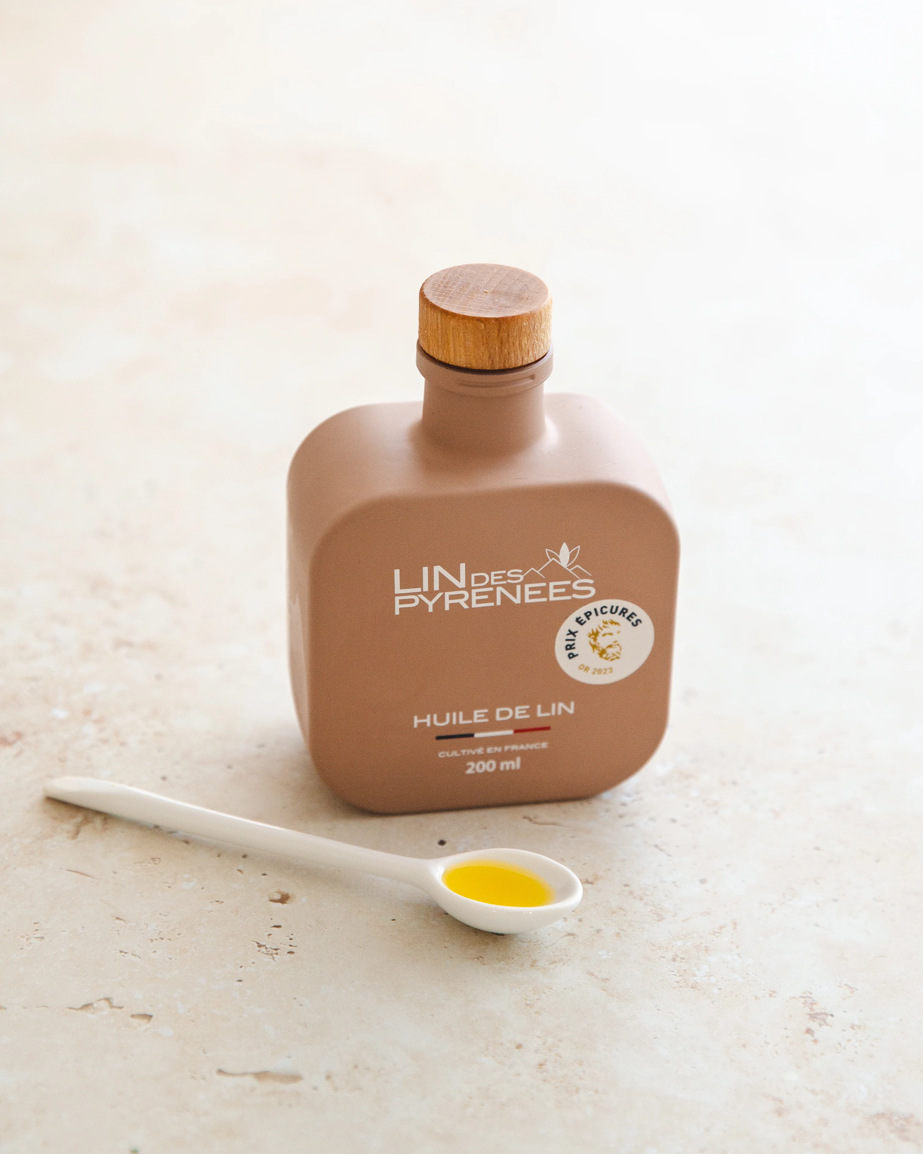 The bottle of virgin linseed oil and its spoon, on a light background